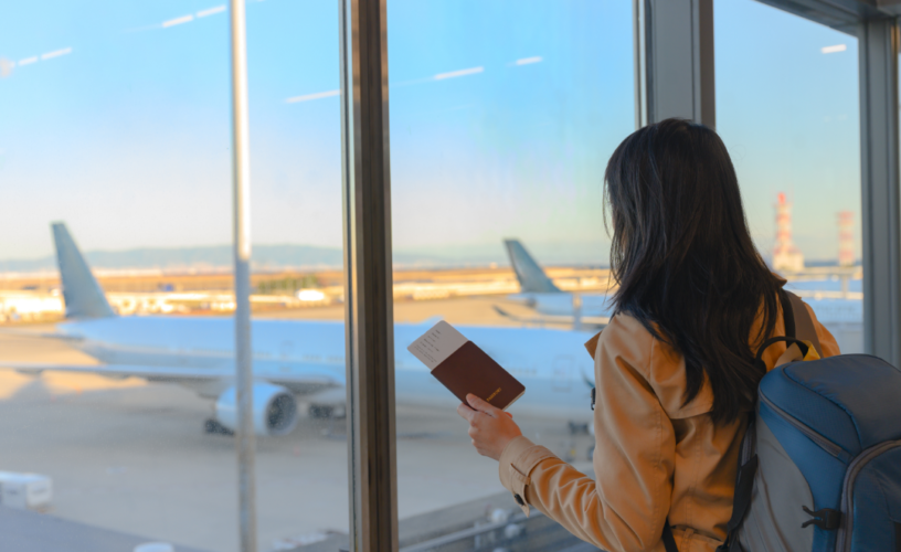 Imagem de uma mulher olhando o avião em aeroporto